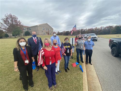 Board members and Dr. Nichols with teachers holding flags 